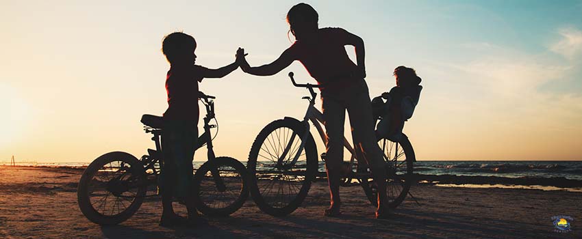Happy mother with kids biking at sunset