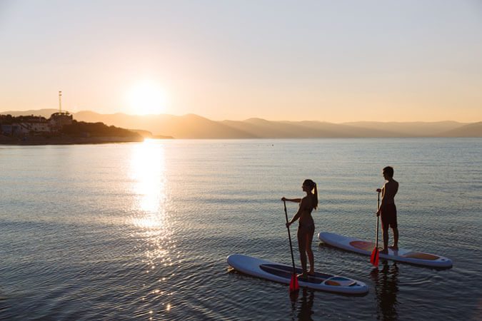 IMR People standing on paddleboard looking at sunset